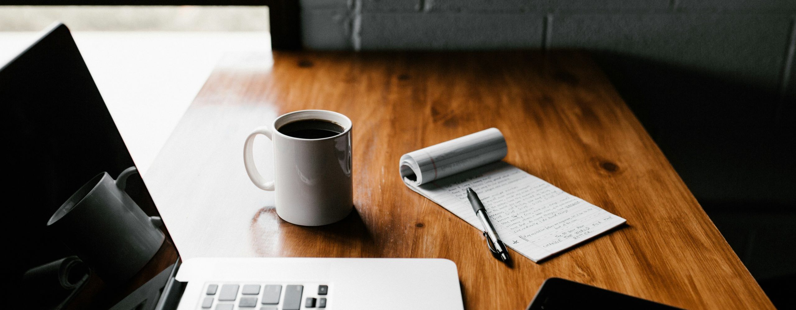 Table with laptop, coffee & notepad with a pan